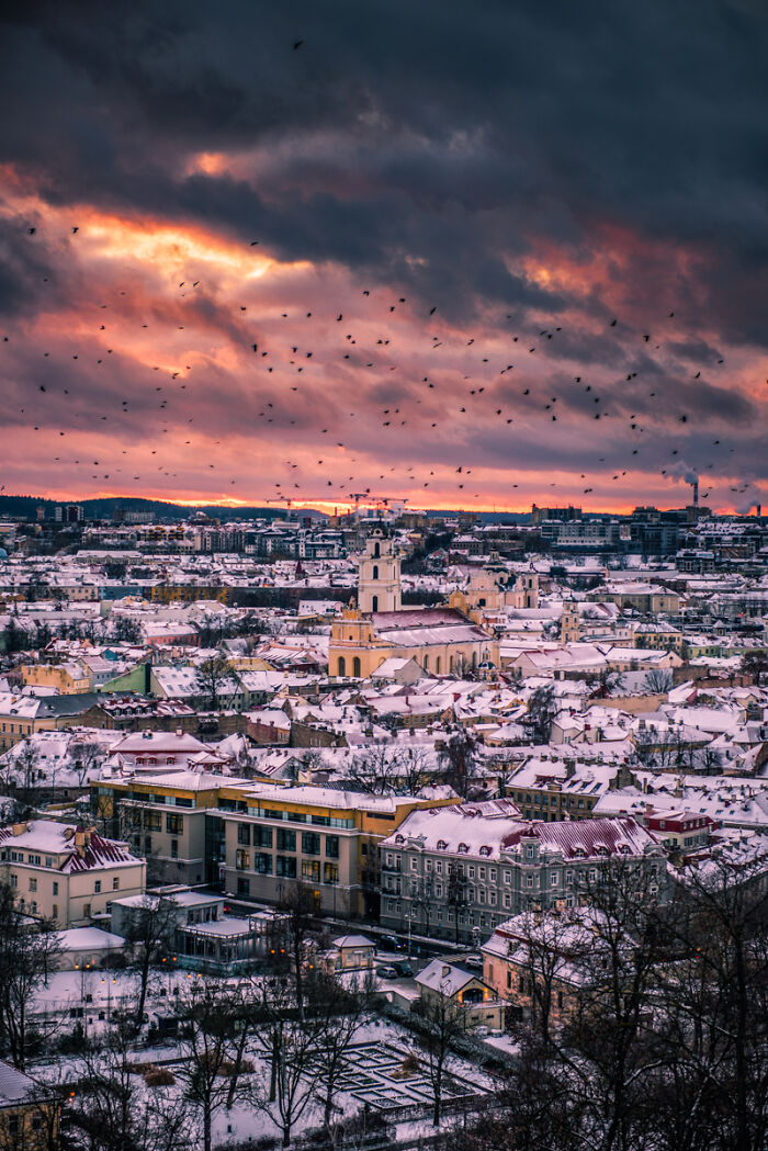 Winter cityscape with snow-covered rooftops and a dramatic sunset sky, a breathtaking travel photo from the community.