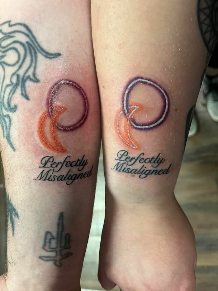 Two matching tattoos with a misaligned design and text reading Perfectly Misaligned on forearms.
