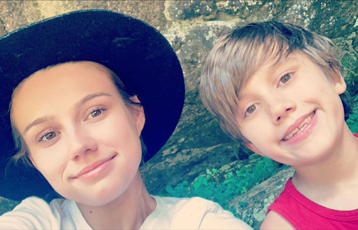 Whitney Purvis with her 16-year-old son outdoors, capturing a close-up selfie with a natural rock background.