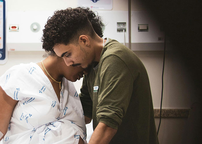 A supportive dad comforting his partner in the birthing room during labor, experiencing the moment firsthand.