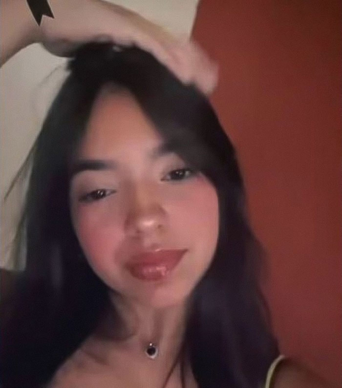 Teen girl posing indoors with long dark hair, wearing a necklace, related to a cake gifted by secret admirer story.