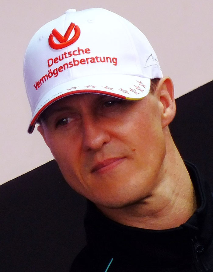 Michael Schumacher wearing a white Deutsche Verm&ouml;gensberatung cap, close-up portrait focusing on his face.