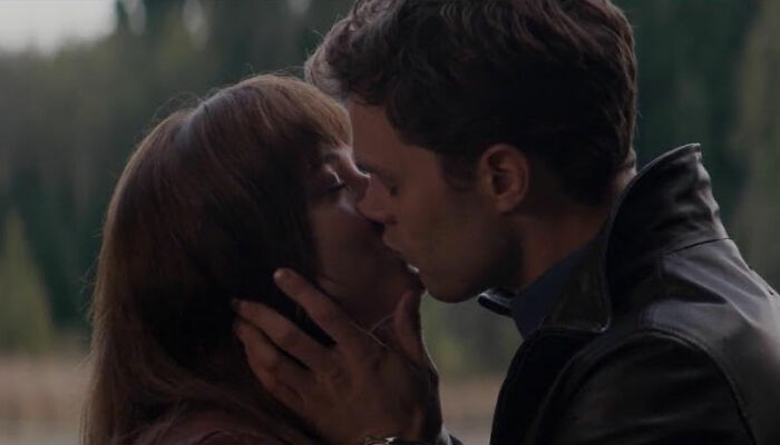 Couple kissing outdoors, portraying a romantic yet potentially toxic relationship scene from popular movies.