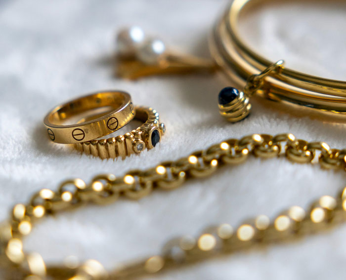 Close-up of gold rings and bracelets on a soft surface, illustrating surprisingly effective old wives' tales about jewelry.