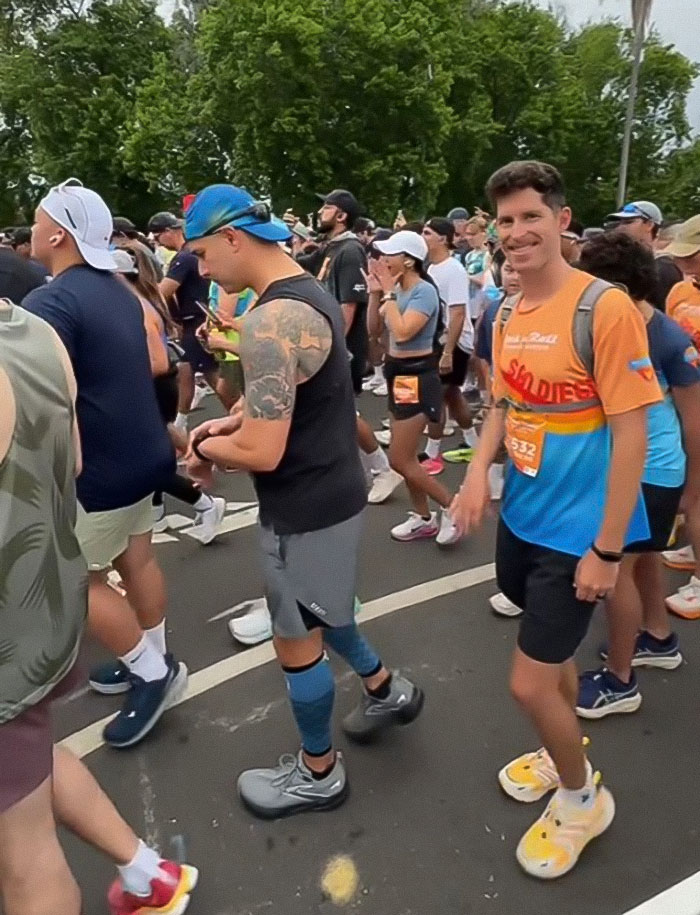 Runners gathering at the starting line for a marathon, including a man in bright athletic gear smiling at the camera.