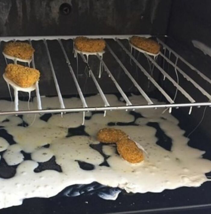 Partially melted cheese dripping from chicken nuggets inside an oven, a cursed picture of food mishap.