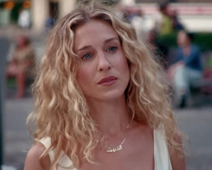 90s star with curly blonde hair outdoors, reflecting on harsh comments during filming that shaped her fashion icon status.