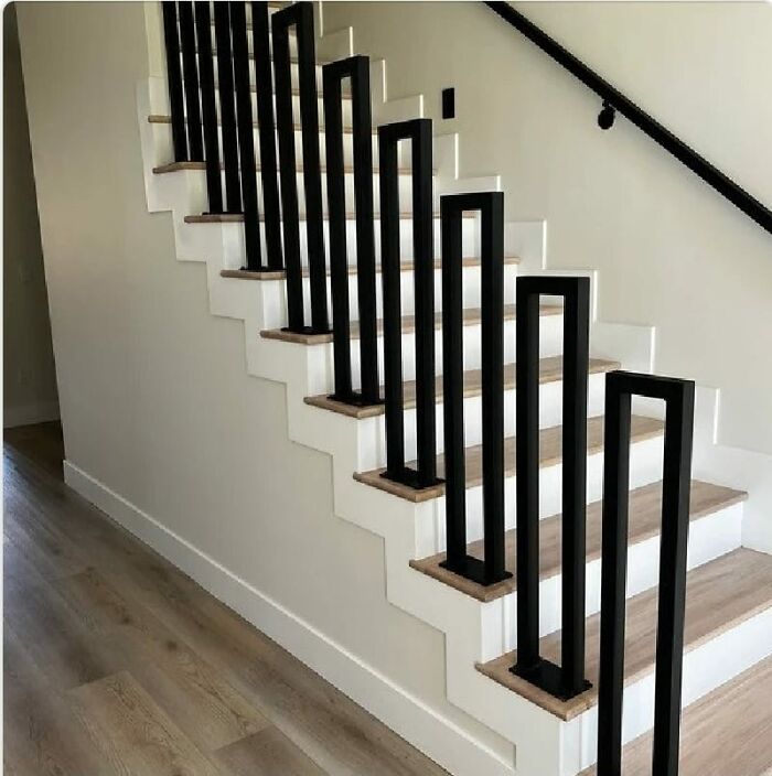 Modern indoor stairs with uneven black railings creating a dangerous and confusing death stairs design.