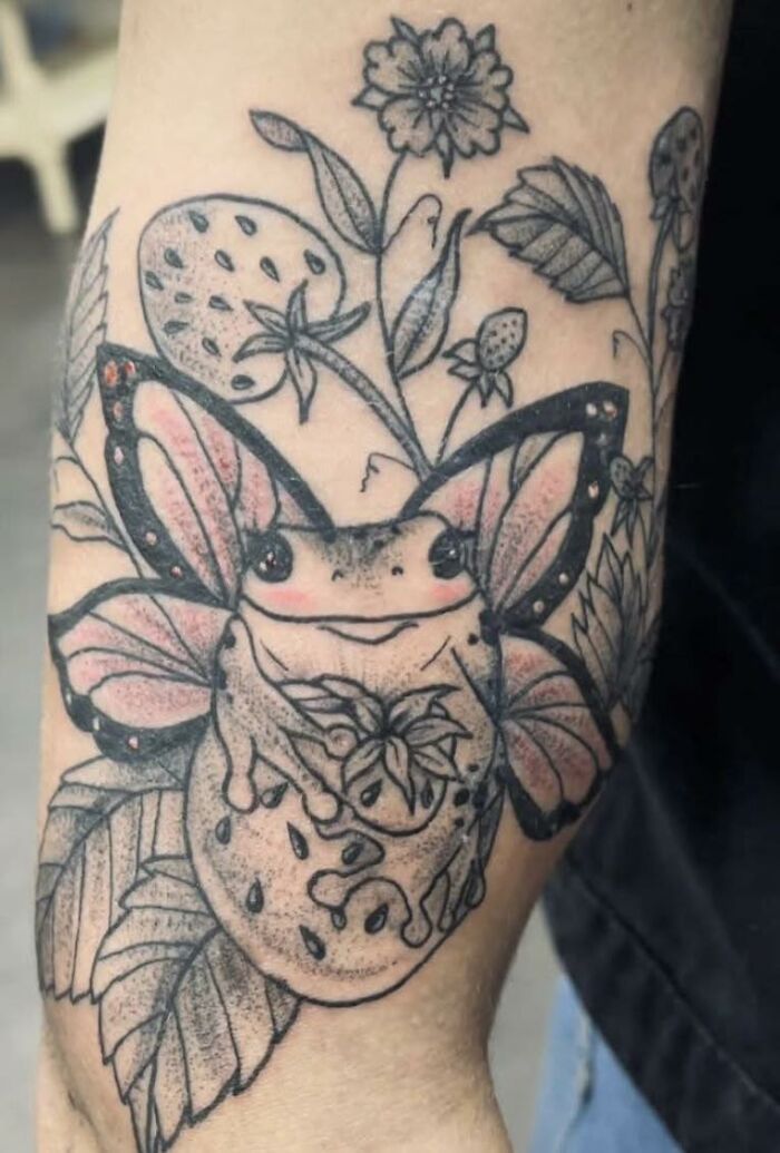 Tattoo of a frog with butterfly wings surrounded by floral designs, an example of a hilariously bad tattoo inkshaming.