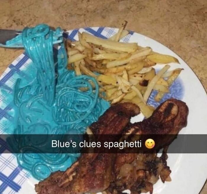 Plate of blue-colored spaghetti with fries and fried chicken, an unusual cursed food picture that might make you go eeeeuw