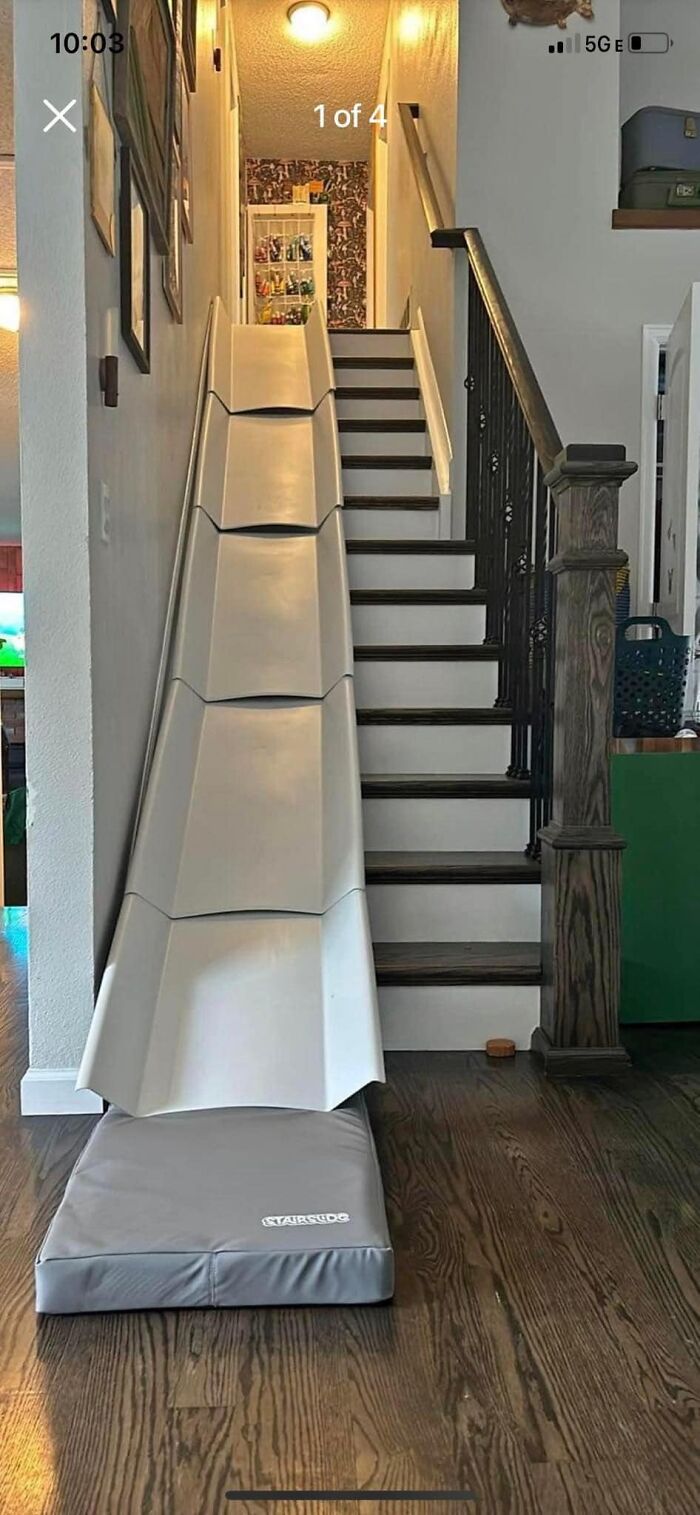 Indoor staircase with a wide plastic slide next to steps, padded mat at the bottom, illustrating a death stairs design.
