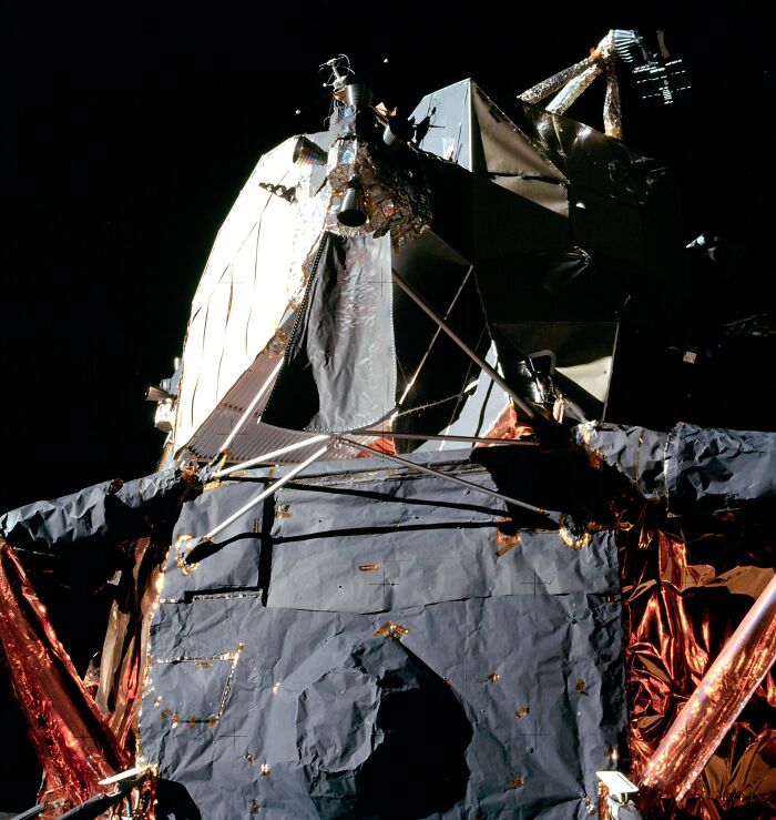 Apollo mission photo showing detailed lunar module surface against the blackness of space during moon landing.