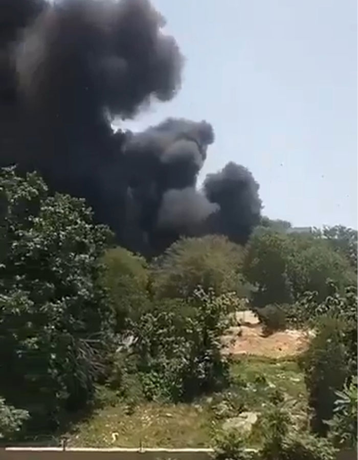Thick black smoke rising above trees after Air India crash, with expert theory on simple mistake causing the tragedy.