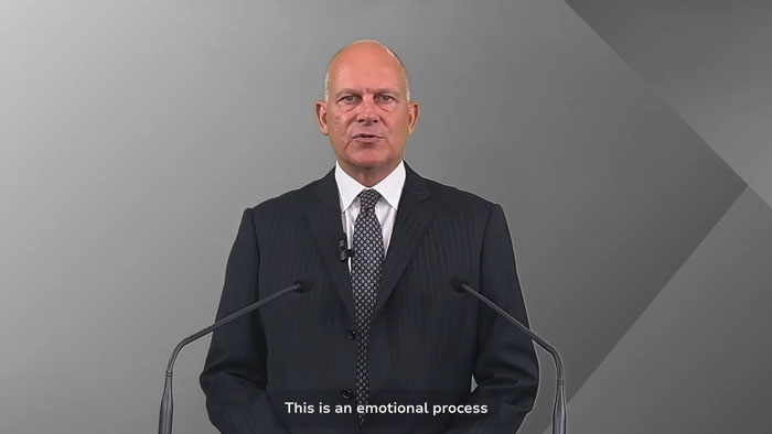 Expert in a dark suit and tie speaking at a podium, sharing theory on simple mistake in Air India crash investigation.