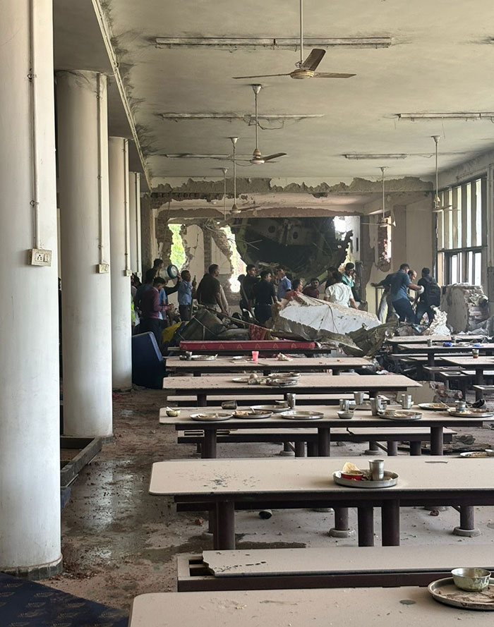 Damaged cafeteria with debris and people inspecting the scene after Air India crash survivor's new interview.