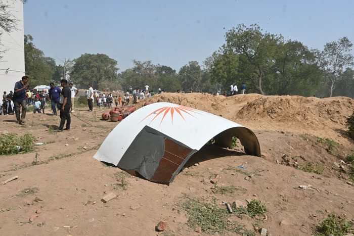 Wreckage of Air India plane amid dirt mounds and people, linked to mysterious object flying off after takeoff theories.