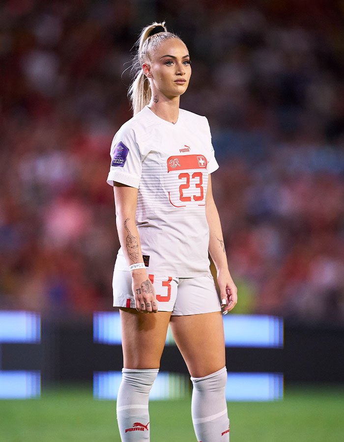 Female national soccer team player in white uniform standing on the field during an intense match against U15 boys team Female national soccer team player in white uniform standing on the field during an intense match against U15 boys team