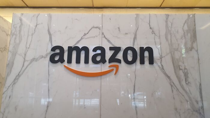 Amazon logo on a marble wall, symbolizing sneaky terms and conditions found by careful readers before signing agreements.