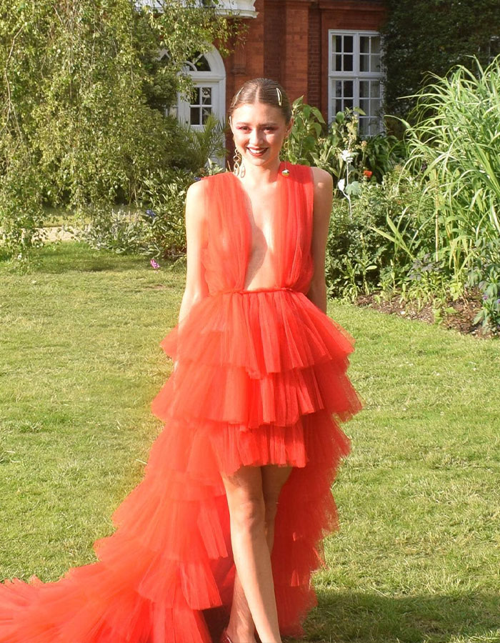 Young woman in a layered red dress standing outdoors, related to anti-vax mom and Cambridge graduate cancer story. Young woman in a layered red dress standing outdoors, related to anti-vax mom and Cambridge graduate cancer story.