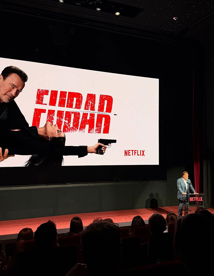 Arnold Schwarzenegger at Netflix premiere speaking to audience with FUBAR movie poster in background. Arnold Schwarzenegger at Netflix premiere speaking to audience with FUBAR movie poster in background.