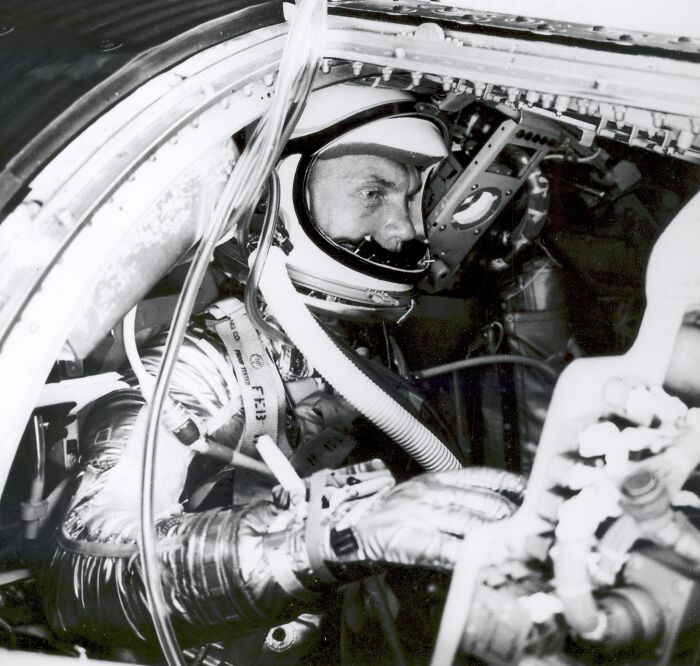 Astronaut in vintage space suit inside spacecraft cockpit surrounded by control panels and equipment showing astronaut facts.