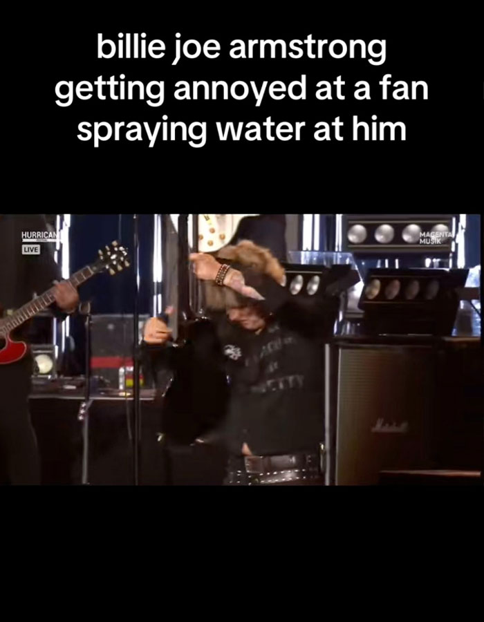 Billie Joe Armstrong of Green Day reacts angrily on stage after a fan sprays water at him during live show.