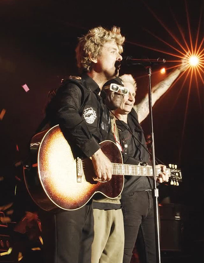 Billie Joe Armstrong of Green Day performing live on stage with guitar during concert, engaging with the crowd.