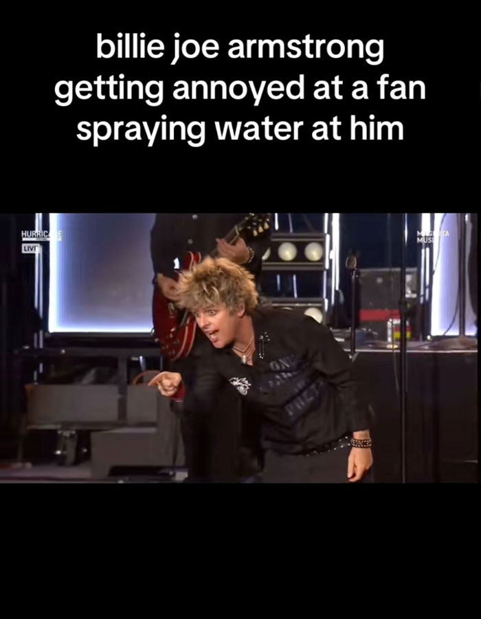 Billie Joe Armstrong of Green Day looking annoyed and confronting a rude fan during a live concert performance.
