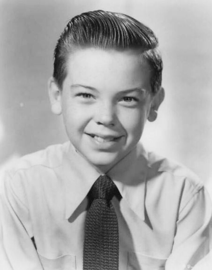 Black and white portrait of a young boy smiling, representing stars lost too soon in the 20th century.