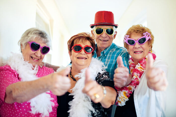 Group of cheerful older adults wearing colorful sunglasses and accessories, giving thumbs up for boomer slang quiz fun. Group of cheerful older adults wearing colorful sunglasses and accessories, giving thumbs up for boomer slang quiz fun.