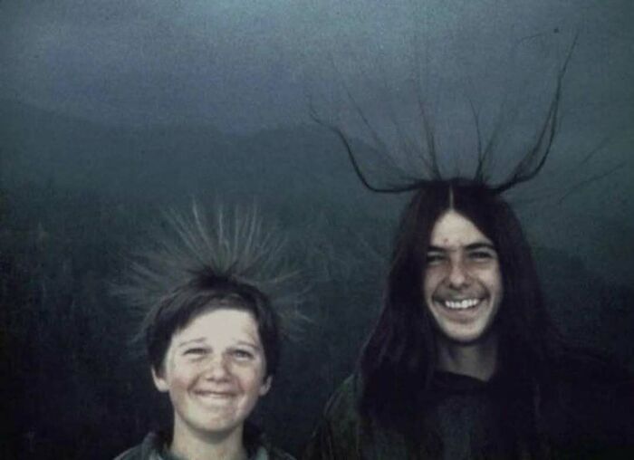 Two young people with hair standing on end, smiling in a historic photo that looks confusing now from history pics.