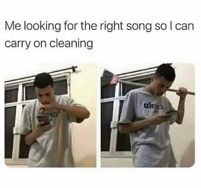 Young man holding a broom and checking phone, showing relatable energy while searching for a song to keep cleaning.