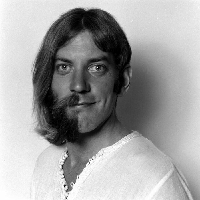 Black and white portrait of a man with half long hair and beard and half clean-shaven, a confusing historical image.
