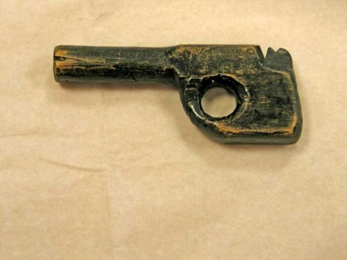 Ancient wooden artifact shaped like a key with a circular hole, showcasing confusing history in old pics.