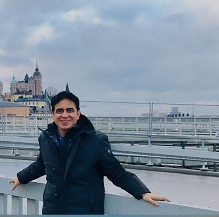 Man in a black jacket standing outdoors with historic buildings in the background, related to Air India pilot final words.