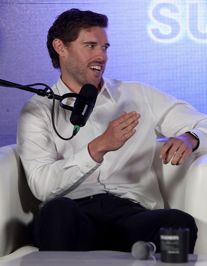 Christopher Schwarzenegger speaking into a microphone wearing a white shirt, showcasing dramatic weight loss during a public event. Christopher Schwarzenegger speaking into a microphone wearing a white shirt, showcasing dramatic weight loss during a public event.