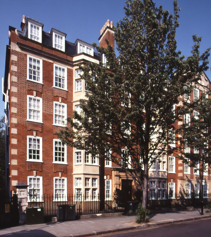 Historic brick apartment building with trees on a sunny street, related to fascinating facts about Princess Diana