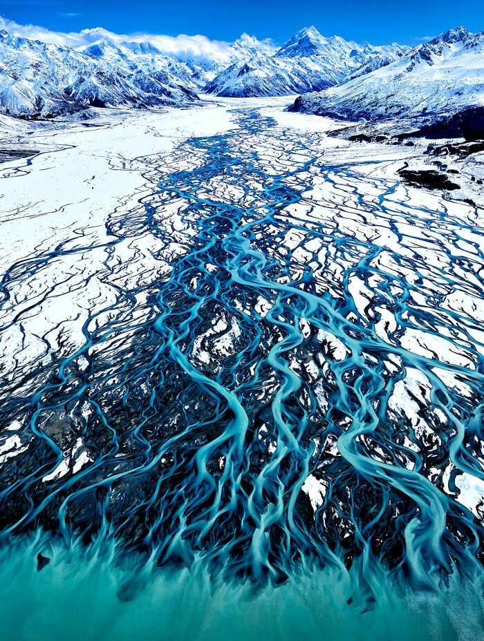 Aerial view of winding blue glacial rivers flowing through snowy mountains showcasing stunning color photography.