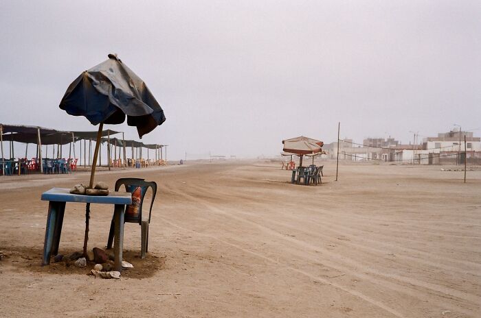 Deserted beach scene with weathered umbrellas and chairs showcasing stunning color photography at the 1839 awards.