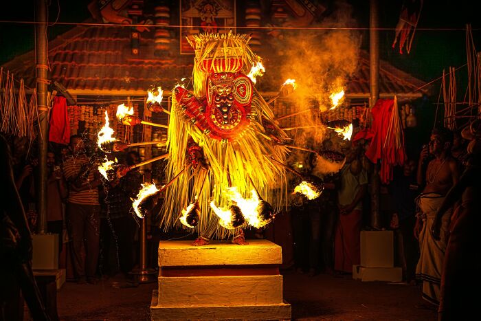 Vibrant color photography of a traditional fire dance performance with dancers in elaborate costumes and flaming props.