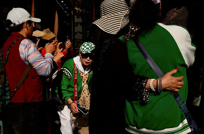 Photographer captures candid street moments full of emotion as people interact and take photos in vibrant urban setting.