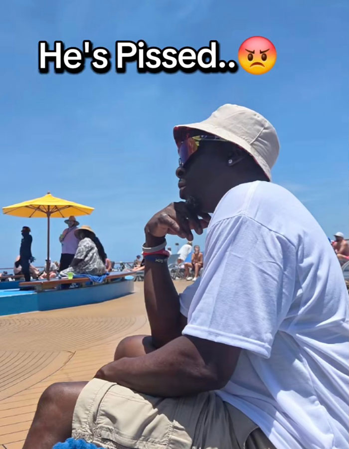 Cruise passenger looking upset while sitting outdoors near pool, frustrated over pineapple shirt&rsquo;s x-rated meaning.