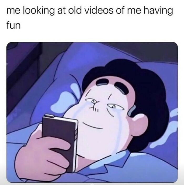 Cartoon character lying in bed, smiling and crying while watching old videos, capturing relatable energy emotions.