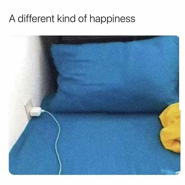 Bed with blue pillow and sheet, phone charger plugged into wall outlet, relating to relatable energy and memes humor.