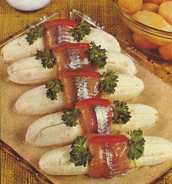 Unusual historical dish with bananas, fish fillets, parsley, and red pepper, showcasing confusing vintage food presentation.