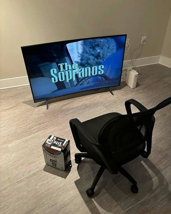 Minimalist room setup with a TV showing The Sopranos, a chair, and a beer pack, illustrating a random fun fact of simple entertainment.