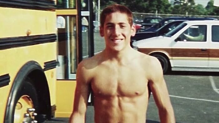 Young shirtless man smiling outdoors near a school bus, illustrating weird things about history on Instagram.