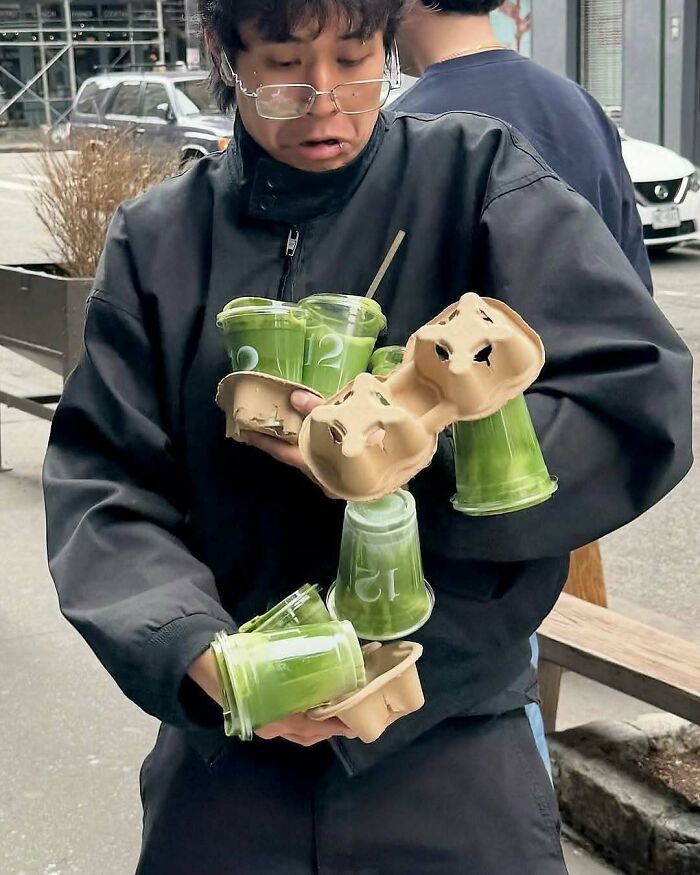 Person struggling to carry multiple green drinks outdoors, illustrating a bizarre moment in nature and animals fun facts.