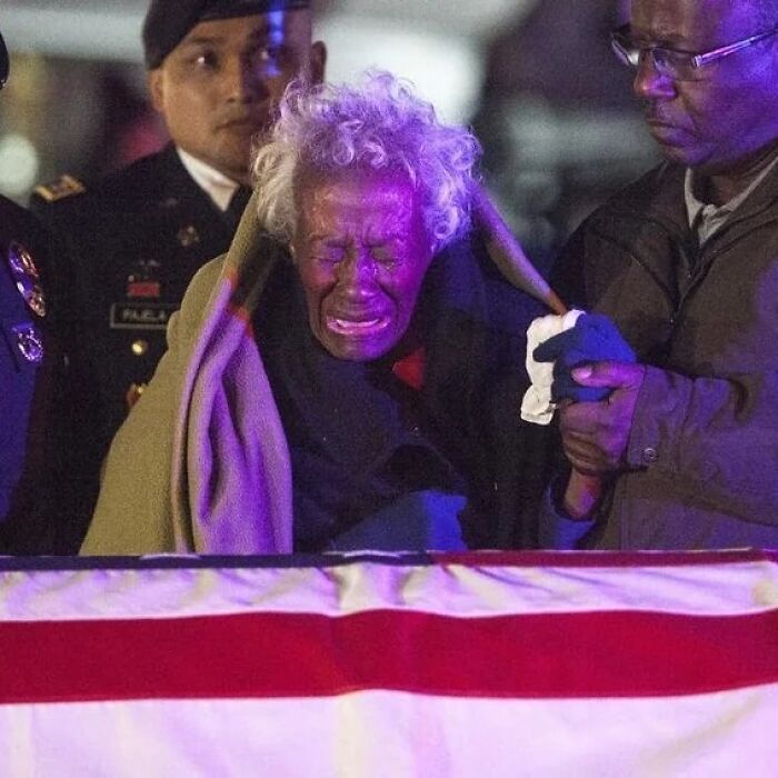 Elderly woman crying while being supported by two men at an event, illustrating weird things about history.