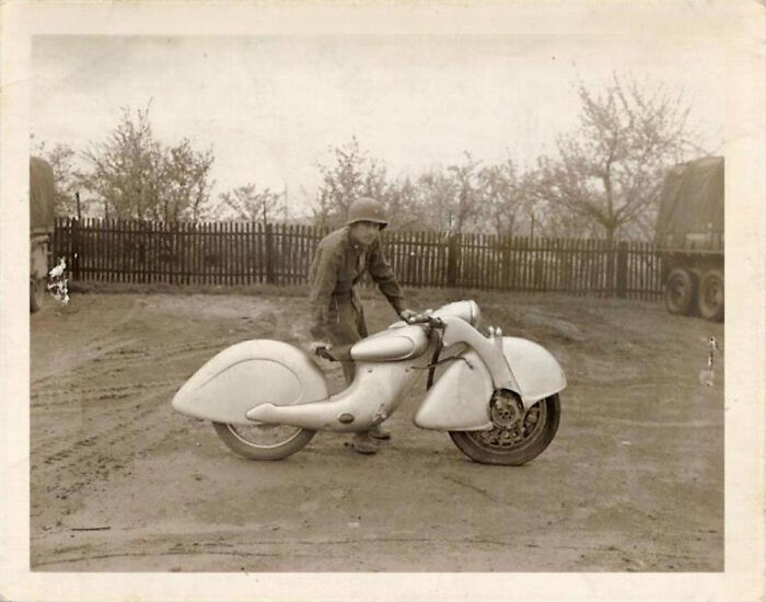 Vintage photo of a soldier with a unique retro motorcycle from history that looks confusing now in old black and white style.